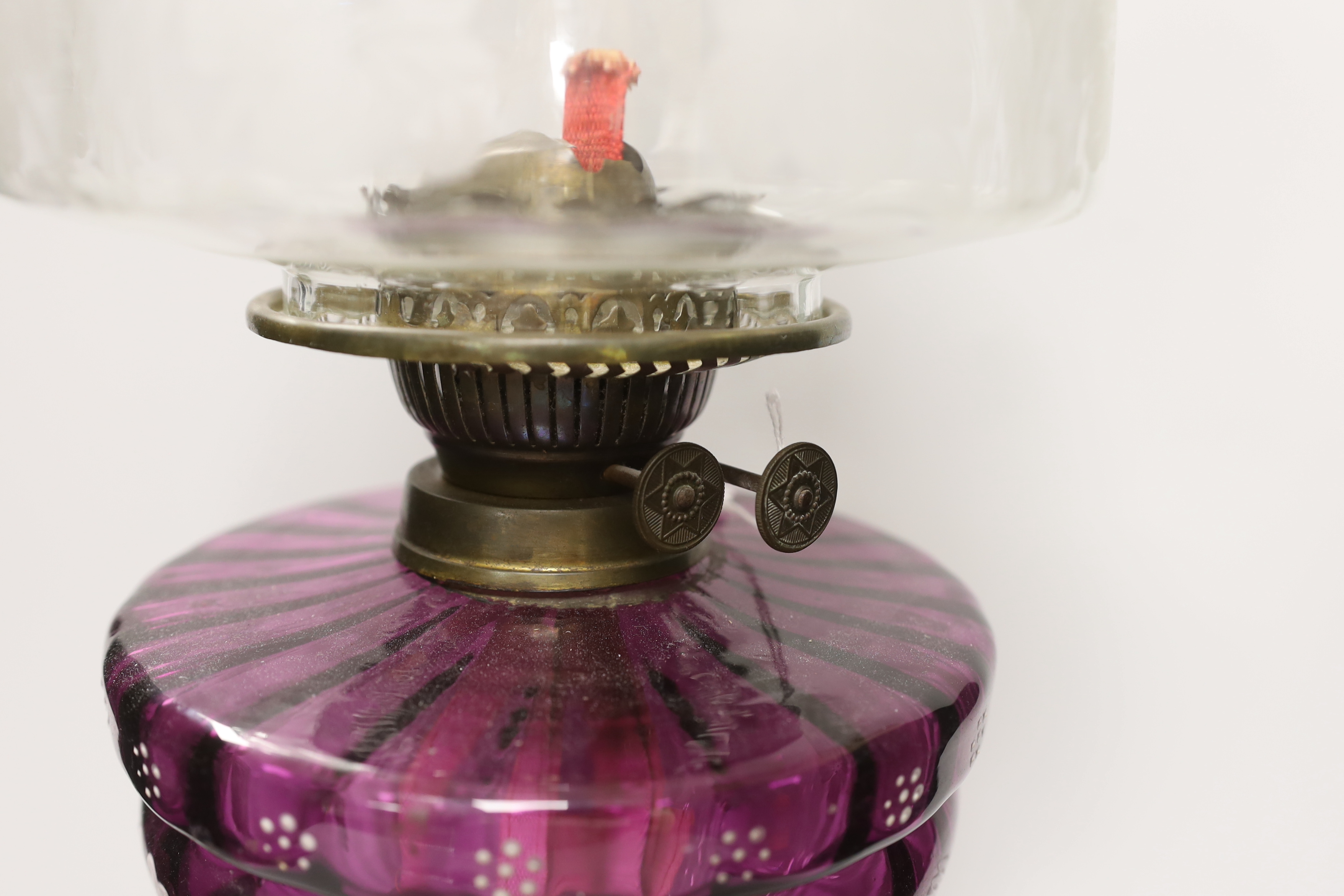 A Victorian oil lamp with an amethyst floral enamelled glass bowl and clear etched shade, 65cm high